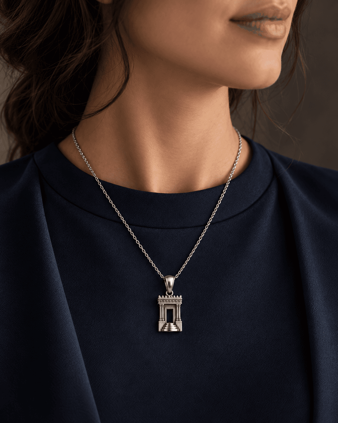 Silver architectural pendant worn with deep navy fabric